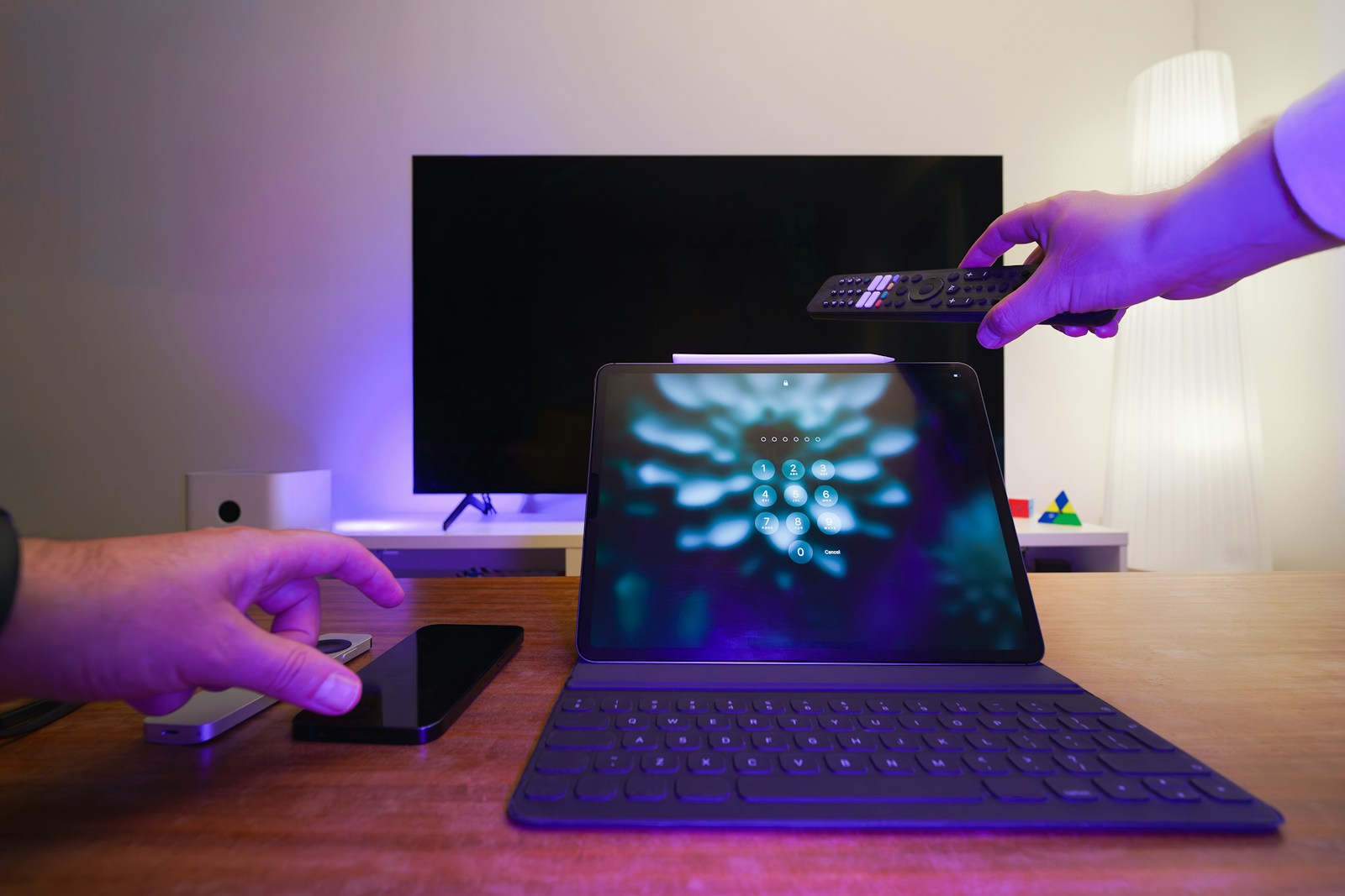 Persoon die thuis IPTV instelt met tv, tablet, smartphone en afstandsbediening